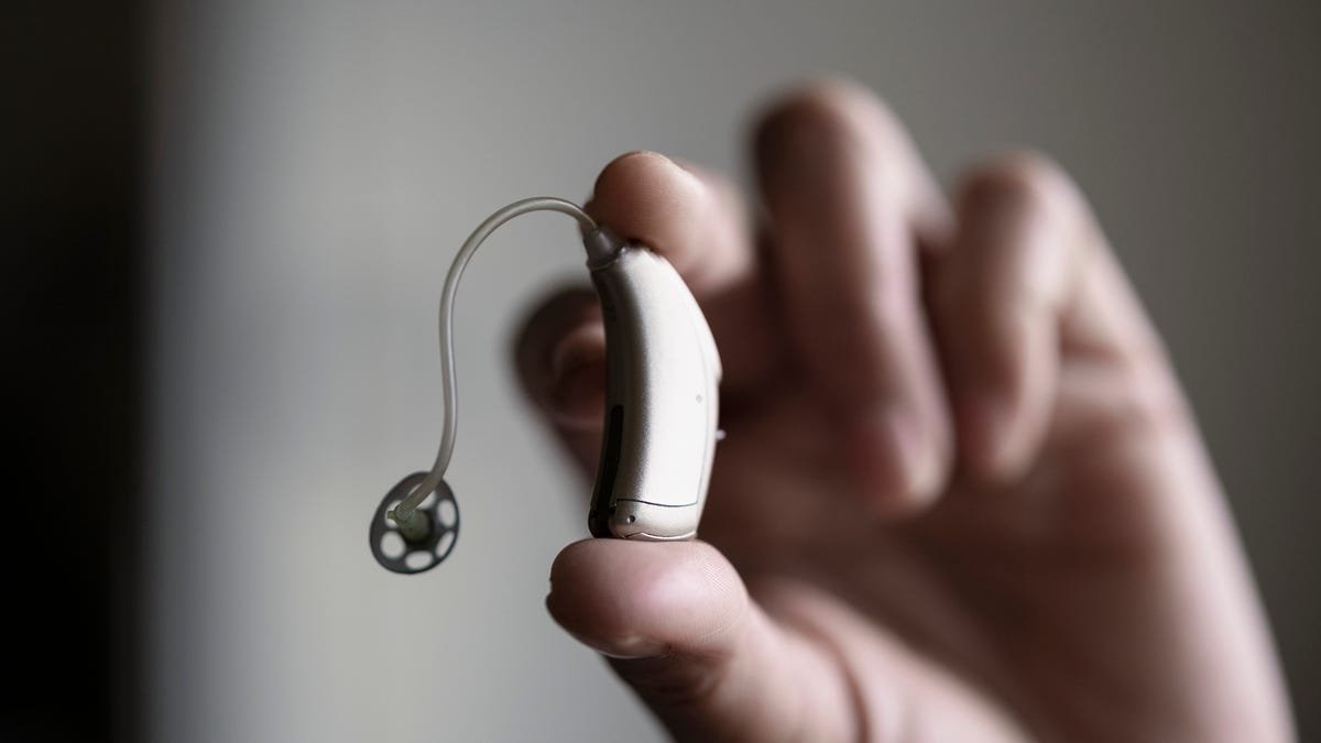 Hand holding behind-the-ear hearing aid