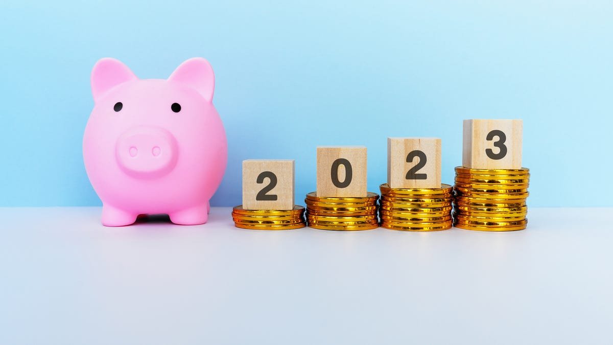 Pink piggy bank with a blue background and four stacks of coins with 2023 across each stack.