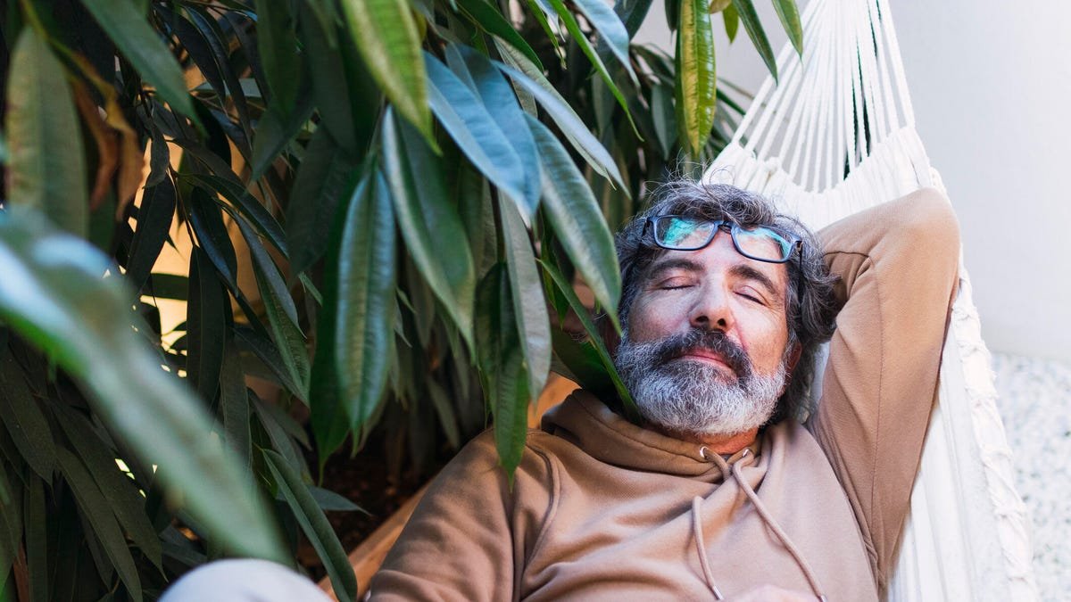 Senior man napping in a hammock in the backyard