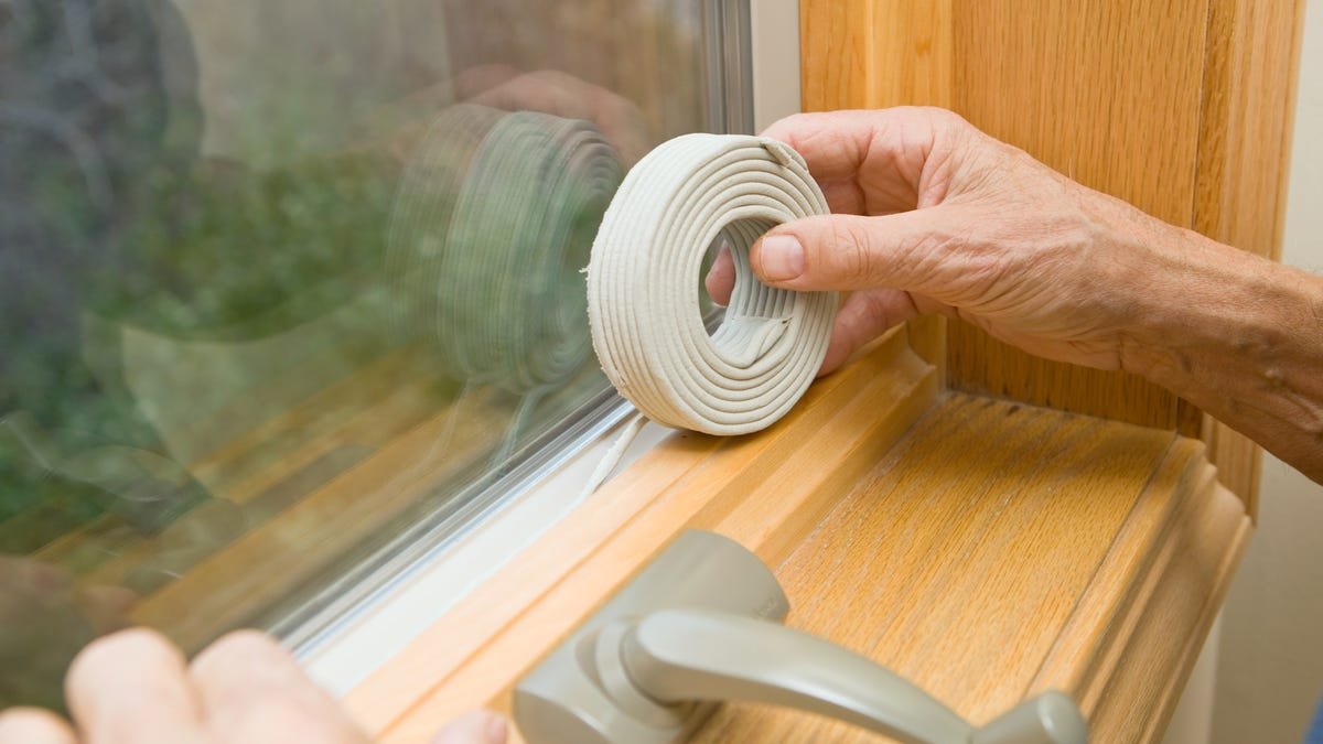 Hands applying weather seal caulk to window frame