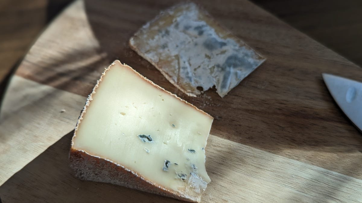 cheese on cutting board with moldy rind having been removed