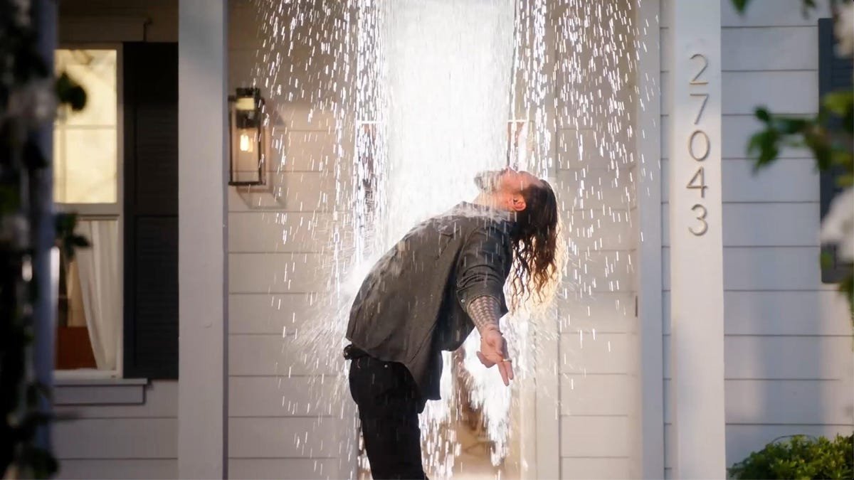 man arches back as water splashes over him.