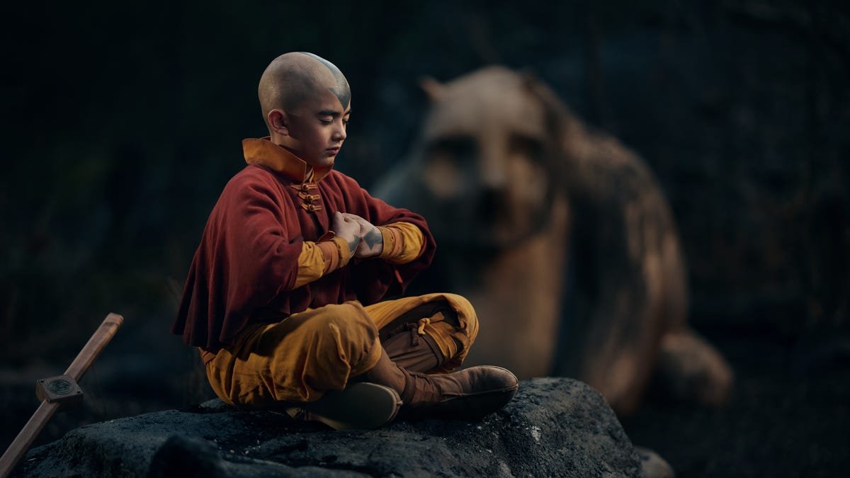 young boy meditates while sitting on a rock