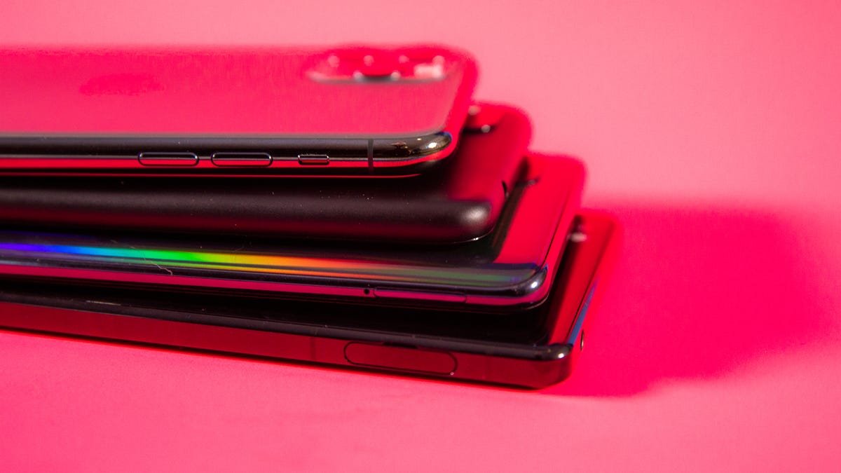 stack of colorful phones against a pink background